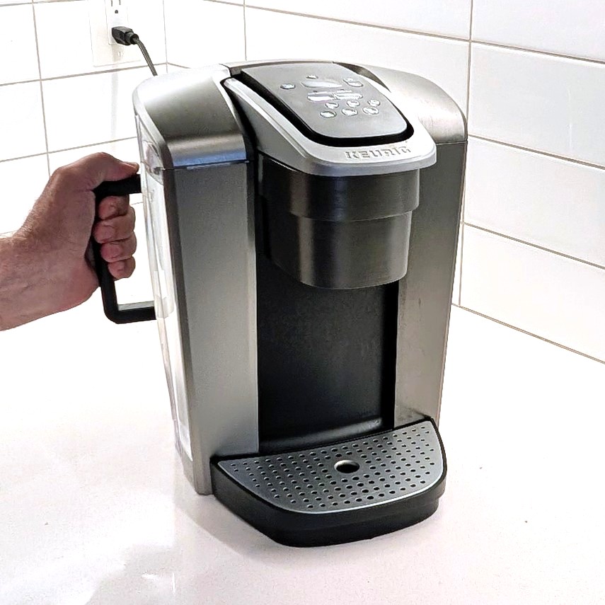 Hand gripping Ergo-K on the exterior of a coffee-maker reservoir